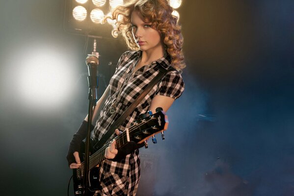 The singer poses on stage with a guitar