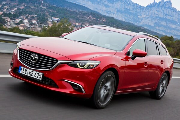 Mazda rojo en el hermoso fondo de las montañas