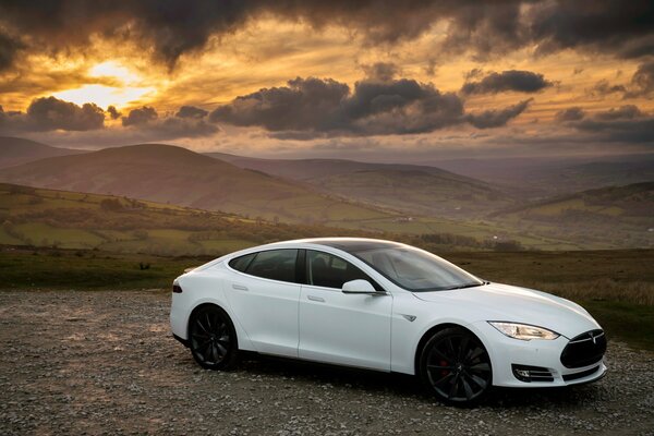 White Tesla at sunset in the mountains