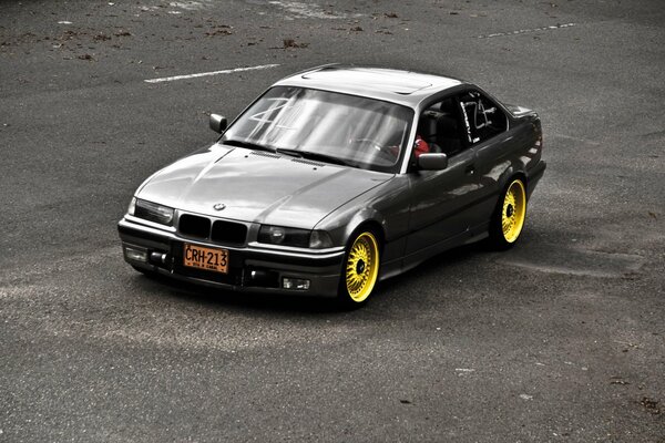 Black BMW with yellow wheels on the road