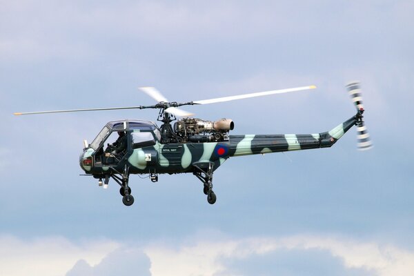 Camouflage helicopter on a light sky background