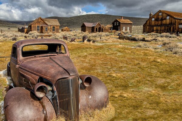 Coche viejo oxidado contra el fondo de las casas de madera