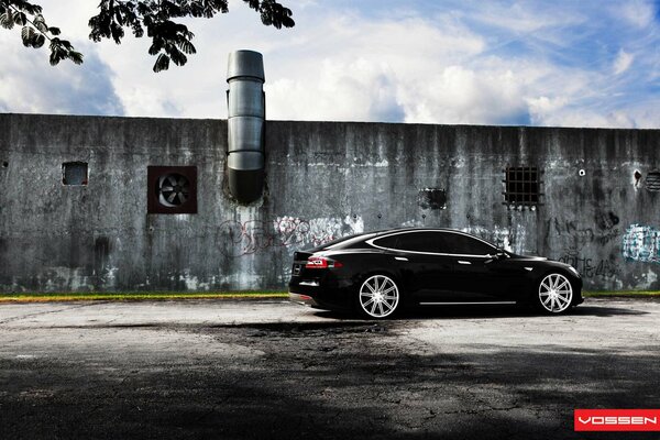 Schwarzes Tesla Model S auf Wandhintergrund