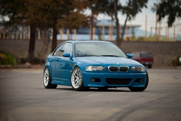 Niebieskie bmw M3 na tle palm