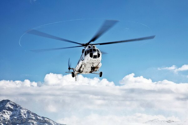 White helicopter on the background of a mountain and a clear blue sky