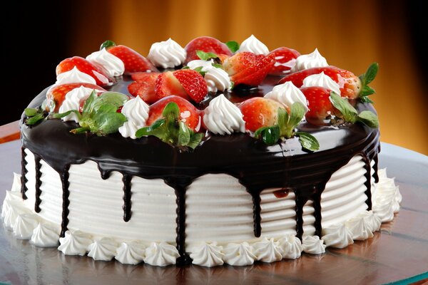 Pastel de cumpleaños con glaseado de chocolate, crema, hojas de menta y fresas