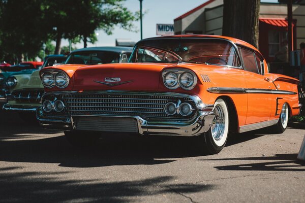 Fresco coche naranja retro de pie en la calle