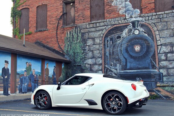 White Alfa Romeo against the wall with a picture of a steam locomotive
