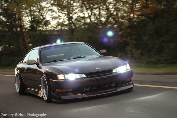 Nissan Silvia púrpura en movimiento en medio de la carretera y el bosque