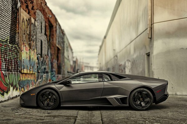 Czarne Lamborghini przy ścianie z grafitem