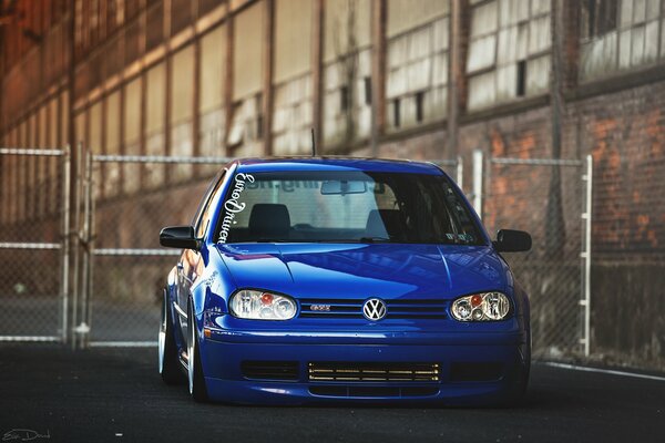 The blue Volkswagen is parked at the old building