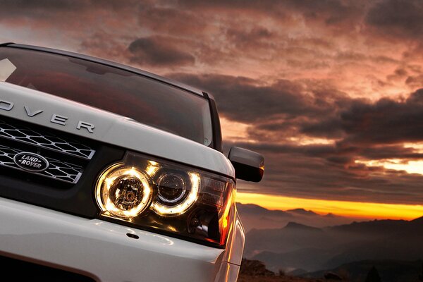 Voiture blanche au coucher du soleil de montagne. Range Rover avec nouveaux phares