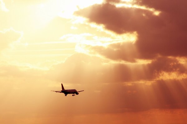 В лучах солнца сквозь облака летит самолёт
