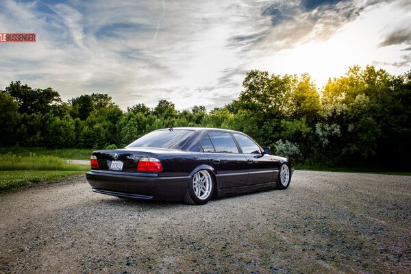 Bmw e38 on a dirt road near the forest