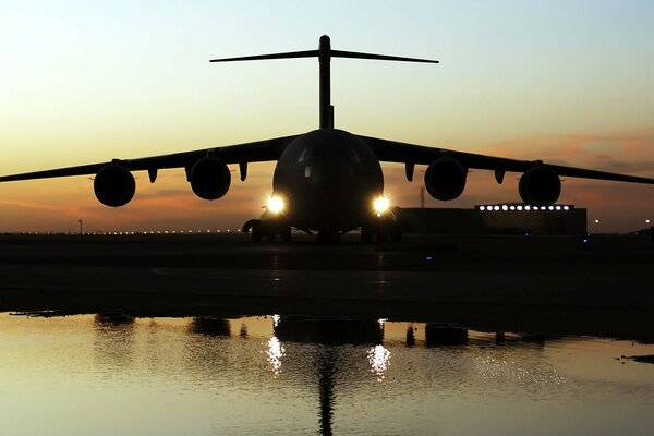 Avión militar que aterriza al anochecer