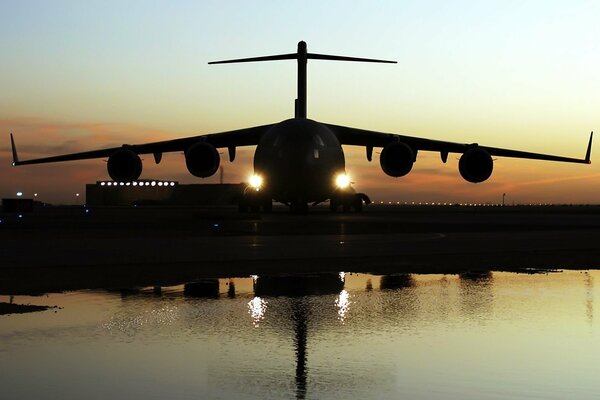 Airplane lights are visible on the runway in the evening