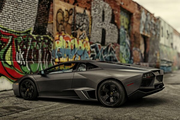 Czarne Lamborghini na tle ściany z grafitem