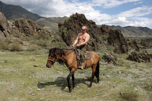 Il presidente russo Vladimir Putin seduto su un cavallo sullo sfondo delle montagne