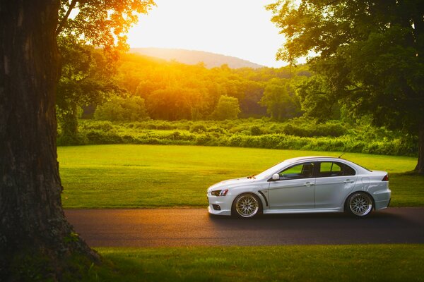 A white car is driving on the road on a green background