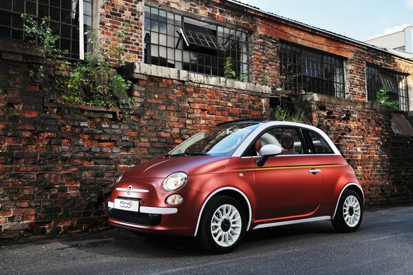 Coche rojo de pie de ladrillo contra la pared