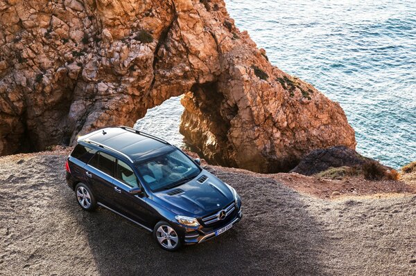 Blue Mercedes amg gle 63s 4matis w166 on the background of rocks and the sea