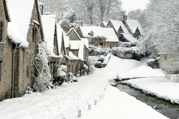 Englands schneebedeckte Häuser am Bach entlang