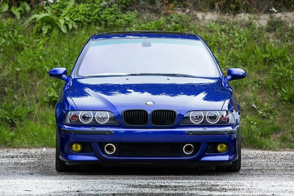 Blue BMW car on a green hill background