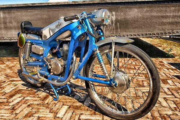 Moto Vintage bleu sur une promenade pavée