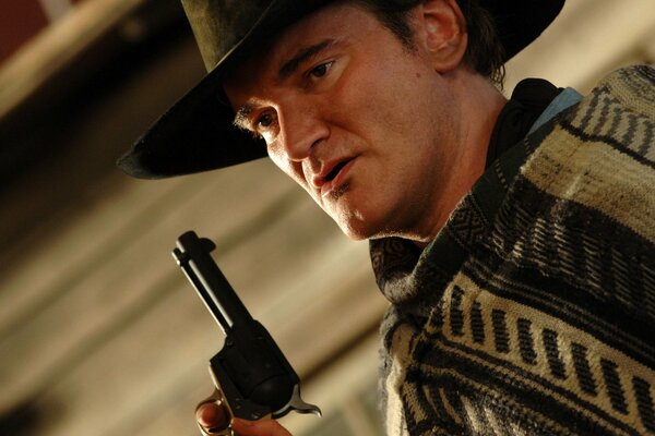 Quentin Tarantino in a hat with a revolver in his hand