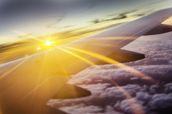 An airplane wing above the clouds at sunset