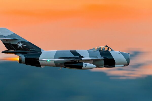 A bomber is flying in the sky at sunset