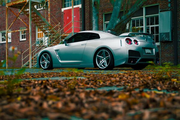 Silver Nissan car on the background of autumn leaves