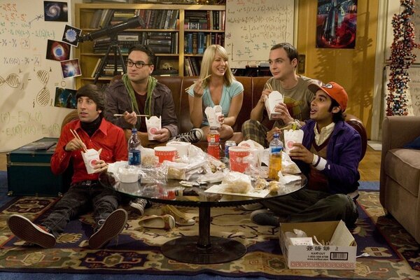 Actors from big bang theory eat while sitting at a table