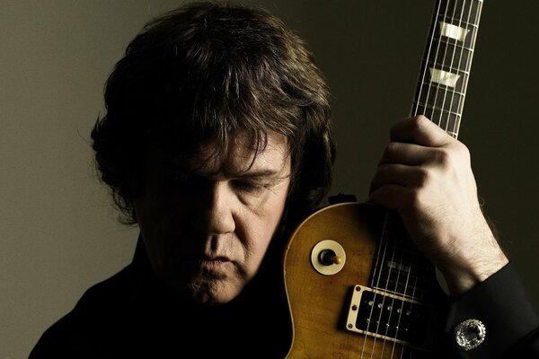 Portrait of Gary Moore holding a guitar