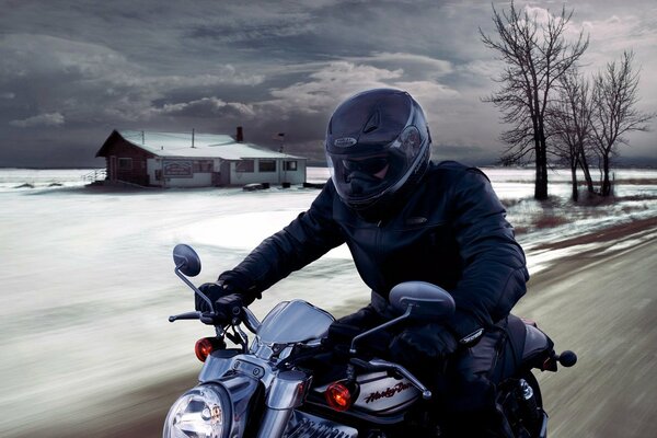 Ein Mann mit einem Helm auf einem Motorrad vor dem Hintergrund einer Winterlandschaft