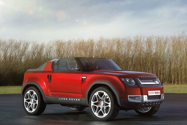 Red land rover on a background of trees