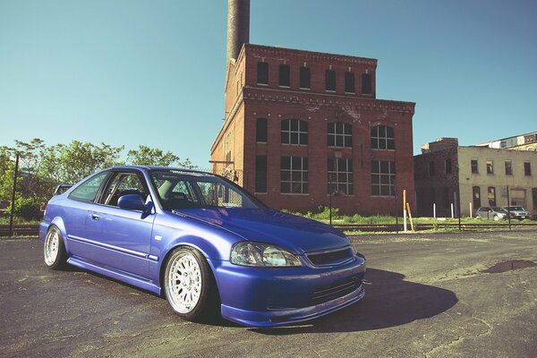 Blue civic on the background of a red building