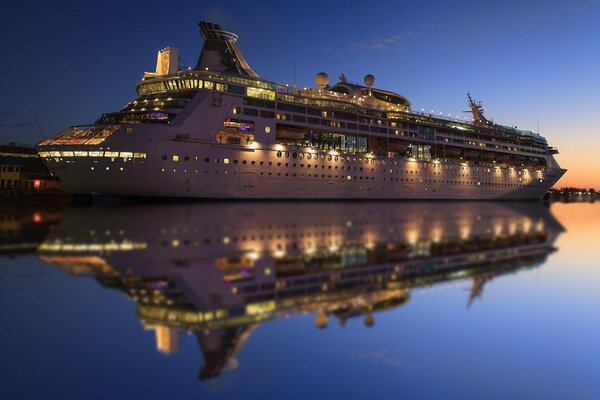 Cruise ship in the evening with lights and reflection on the water