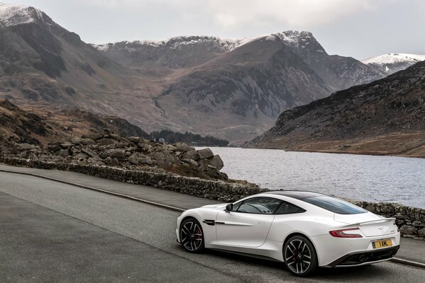 A white car rushes along the highway against the background of mountains