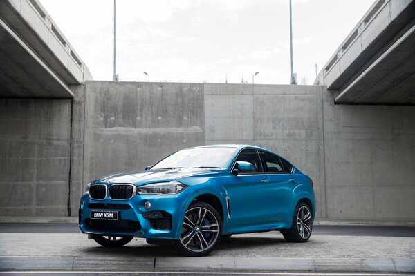 Blauer BMW auf dem Bürgersteig vor dem Hintergrund der grauen Wand