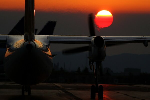 Flugzeug steigt bei Sonnenuntergang vom Aeradrom ab