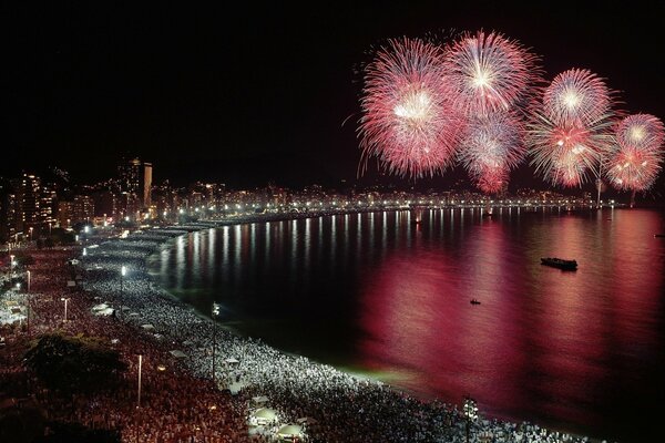 Costa del mare nella notte con le luci della grande città ed il saluto