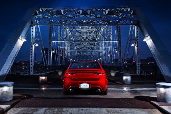 A red car stands on the bridge at night