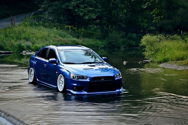 A blue sports car in a puddle