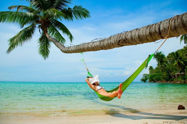 A girl is resting in a hammock on the beach