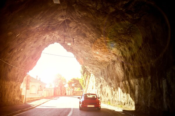 Porsche opuszcza tunel w skale w słoneczny dzień