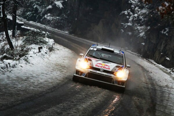 Volkswagen monta en un camino cubierto de nieve a lo largo de los árboles