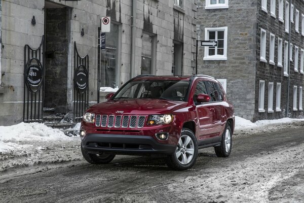 A red Jeep car stands in the middle of the street