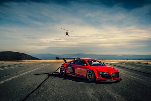 Red helicopter on the road on the background of a car