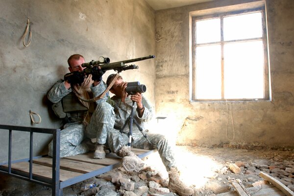 Soldaten mit Gewehren in dem zerstörten Gebäude sind bereit für die Schießerei